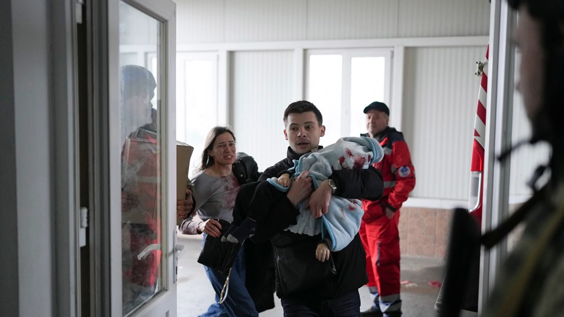 Un padre lleva a su hijo en brazos al hospital en Mariúpol