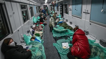 Madres sentadas junto a sus hijos en un vagón de tren transformado para el transporte médico 