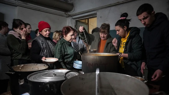 La gente hace cola para recibir comida caliente en un refugio antibombas improvisado en Mariupol La gente hace cola para recibir comida caliente en un refugio antibombas improvisado en Mariupol