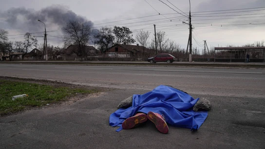 Un cuerpo yace cubierto por una lona en una calle de Mariupol Un cuerpo yace cubierto por una lona en una calle de Mariupol