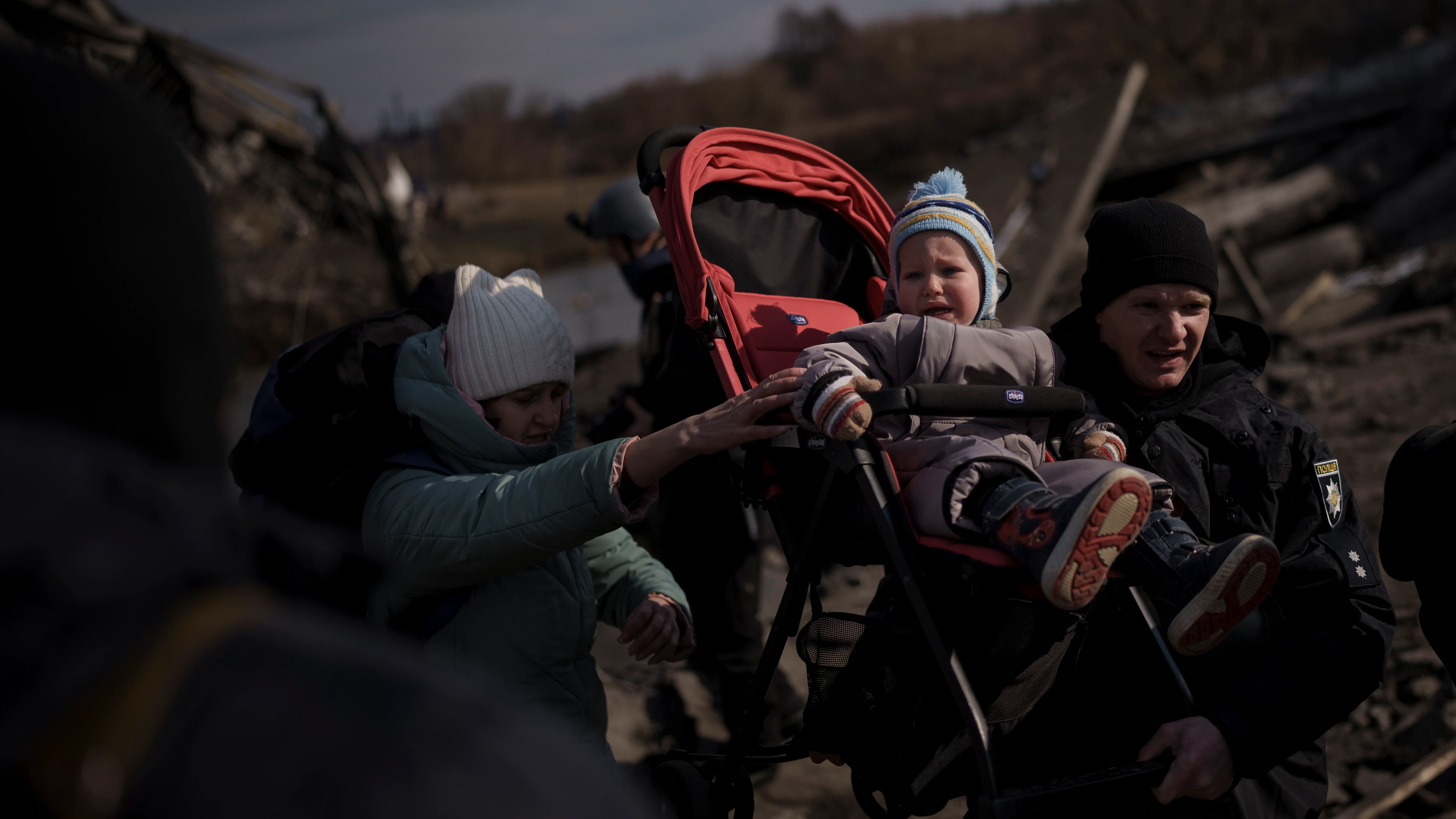 Un niño es llevado en un cochecito por un camino improvisado mientras huye de Irpin, en las afueras de Kiev