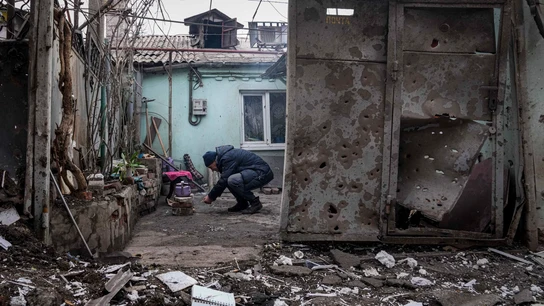 Un hombre enciende un fuego debajo de la tetera en el patio de un edificio de apartamentos afectado por los bombardeos en Mariupol Un hombre enciende un fuego debajo de la tetera en el patio de un edificio de apartamentos afectado por los bombardeos en Mariupol