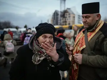 Un sacerdote militar intenta consolar a una mujer que llora y que fue evacuada de Irpin, en un punto de triaje en Kiev, Ucrania.