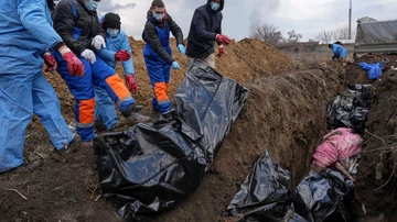 Varias personas colocan cadáveres en una cuneta de Mariúpol