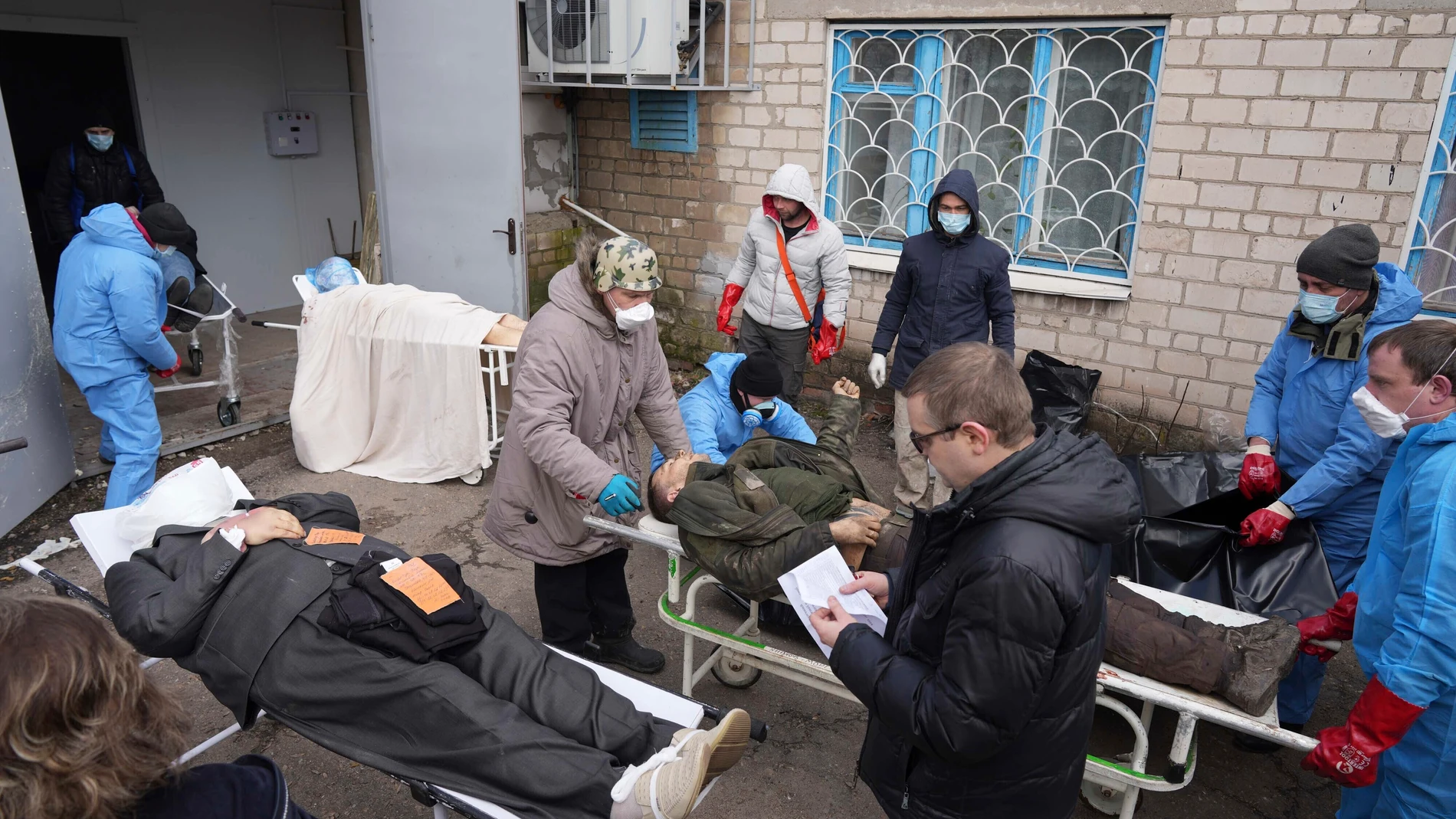 Los cadáveres se preparan antes de colocarlos en bolsas para cadáveres y enterrarlos en una fosa común en las afueras de Mariupol, Ucrania.