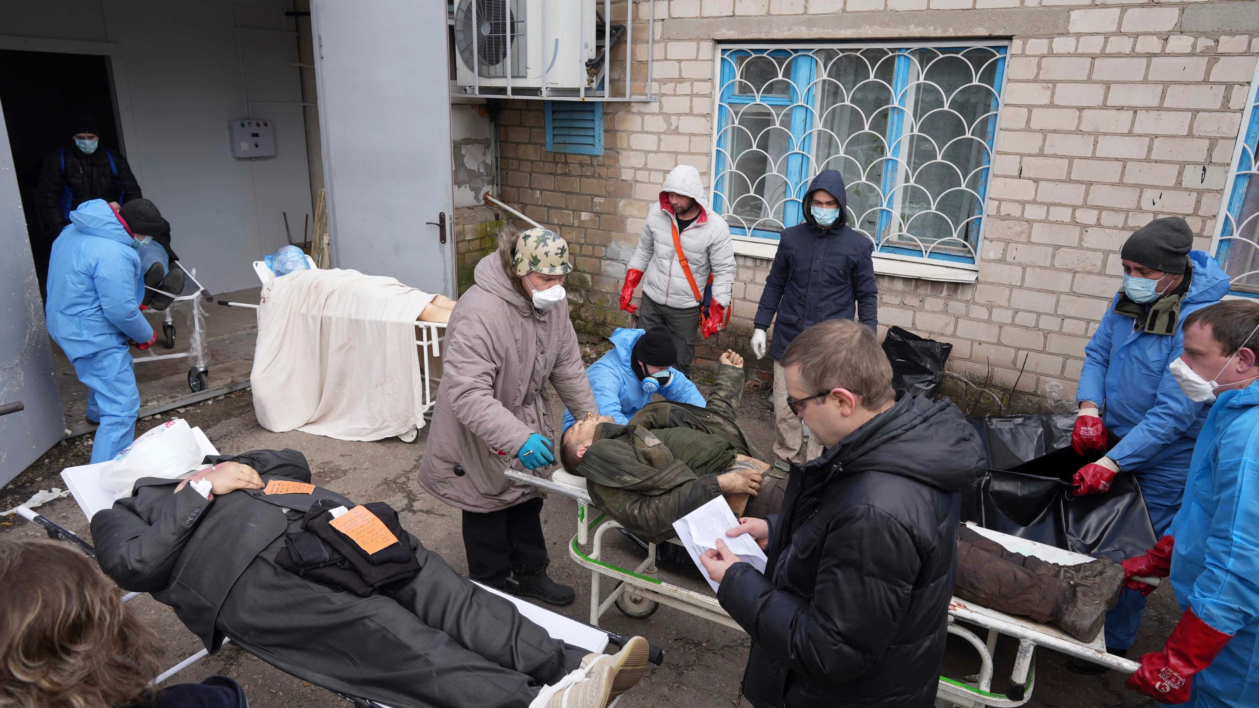 Los cadáveres se preparan antes de colocarlos en bolsas para cadáveres y enterrarlos en una fosa común en las afueras de Mariupol, Ucrania.