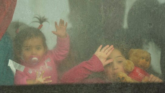 Dos ni&ntilde;as ucranianas saludan desde el autob&uacute;s mientras cruzan el paso fronterizo de Moldavia a Ruman&iacute;a.