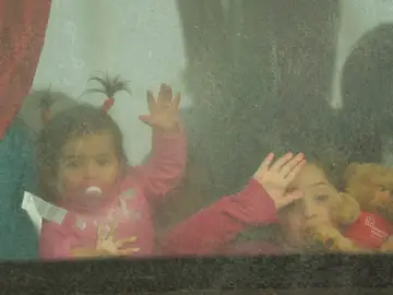Dos niñas ucranianas saludan desde el autobús mientras cruzan el paso fronterizo de Moldavia a Rumanía.