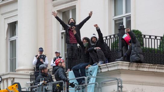  Un grupo de ocupantes ilegales se sienta en el borde de un balc&oacute;n junto a una pancarta que dice "Esta propiedad ha sido liberada".