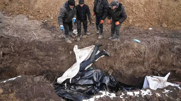 Los cadáveres se colocan en una fosa común en las afueras de Mariupol, Ucrania