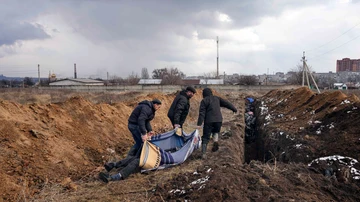 Un grupo de personas traslada los cadáveres de las víctimas de la guerra a una fosa común en las afueras de Mariúpol