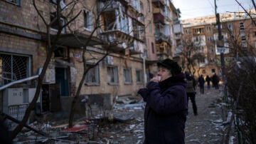 Una mujer mira los edificios residenciales dañados por una bomba en Kiev, Ucrania