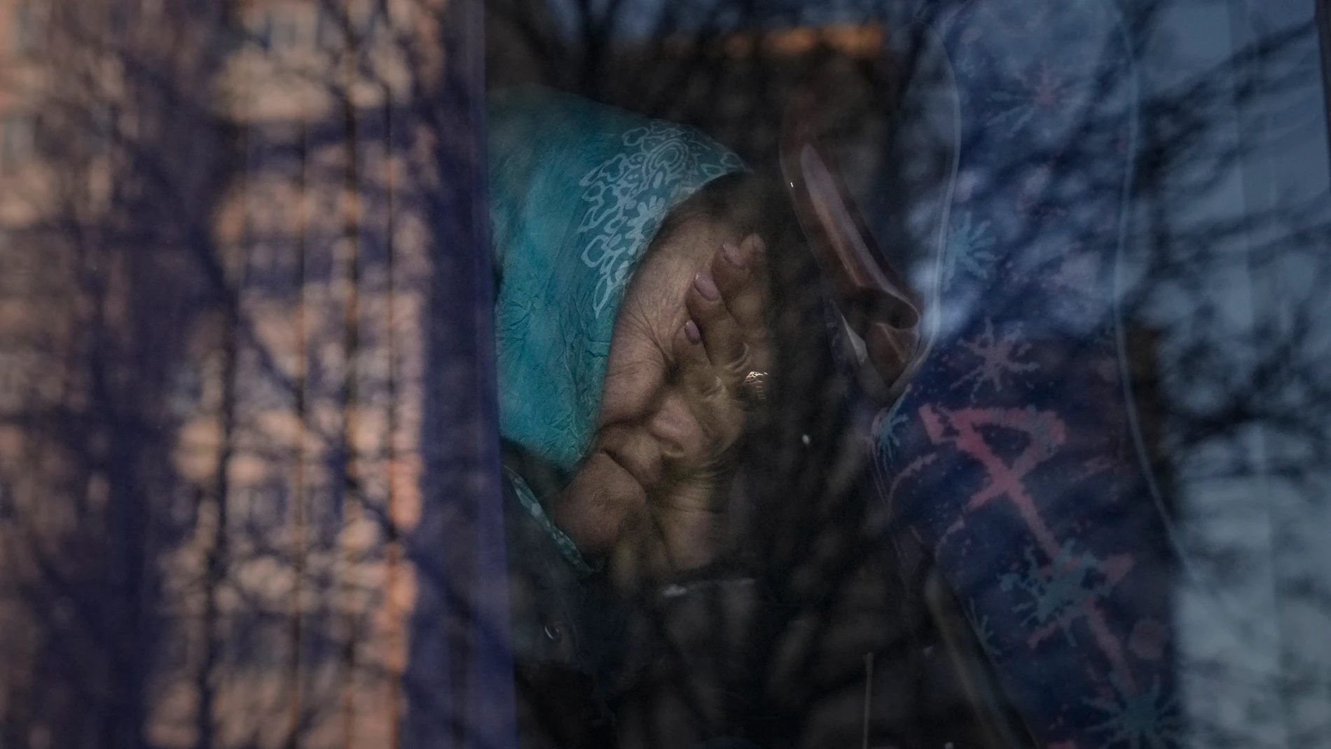 Una refugiada ucraniana llora en el autobús que la evacúa de Ucrania.