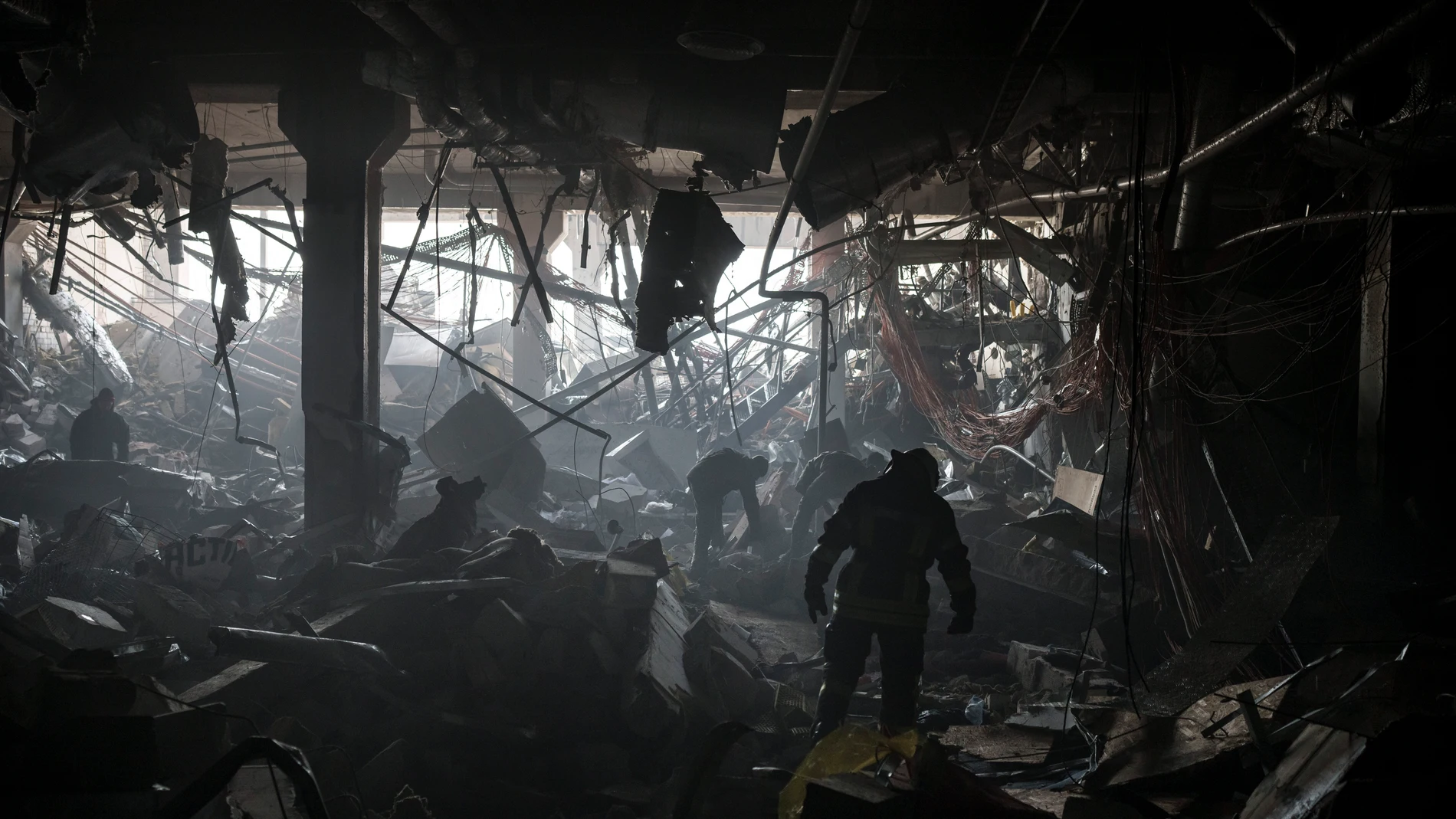 Bomberos y militares ucranianos buscan personas bajo los escombros dentro de un centro comercial después de un bombardeo en Kiev, Ucrania.