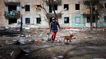 Un ciudadano de Mariúpol pasea junto a su perro entre escombros.