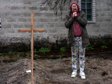 Una mujer llora junto a la tumba improvisada de su padre, muerto en un ataque ruso y enterrado en el jardín de su casa a las afueras de Kiev.