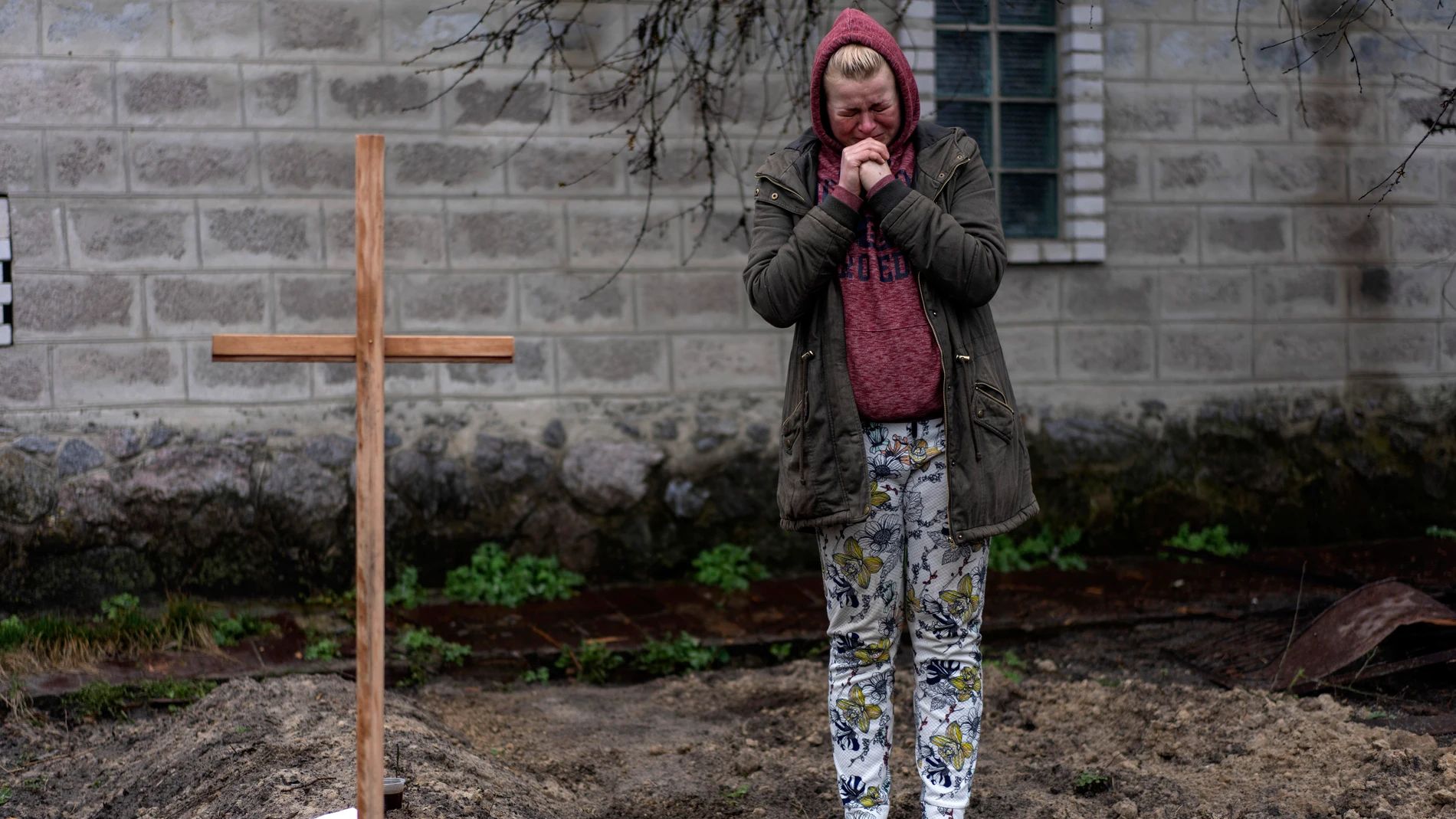 Una mujer llora junto a la tumba improvisada de su padre, muerto en un ataque ruso y enterrado en el jardín de su casa a las afueras de Kiev.