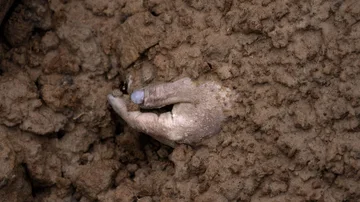 La mano de un cadáver enterrado junto con otros cuerpos se ve en una fosa común en Bucha, Ucrania