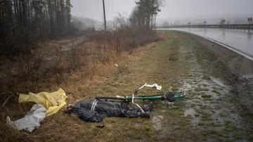 El cuerpo de un hombre yace sobre el pasto junto a su bicicleta en la carretera que ingresa a Bucha, en las afueras de Kiev, Ucrania, el domingo 3 de abril de 2022.
