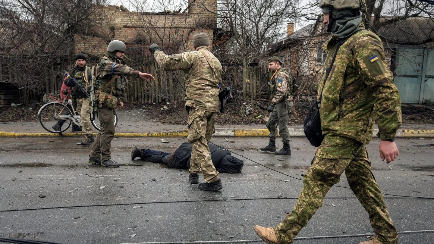 Militares ucranianos buscan explosivos en el cuerpo de un civil en Bucha, Ucrania. Crímenes de guerra