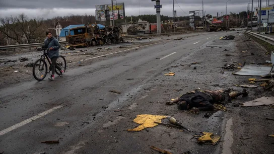 Una mujer camina junto a un soldado ruso muerto en Bucha, Ucrania, el 2 de abril de 2022. Invasión rusa de Ucrania