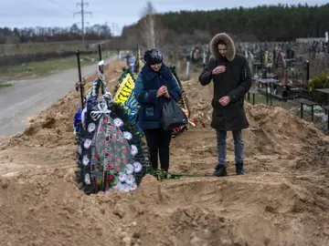 Un madre y su hijo acuden al funeral del marido y padre, asesinado por los soldados rusos en Bucha.
