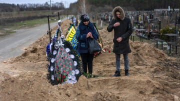 Un madre y su hijo acuden al funeral del marido y padre, asesinado por los soldados rusos en Bucha.