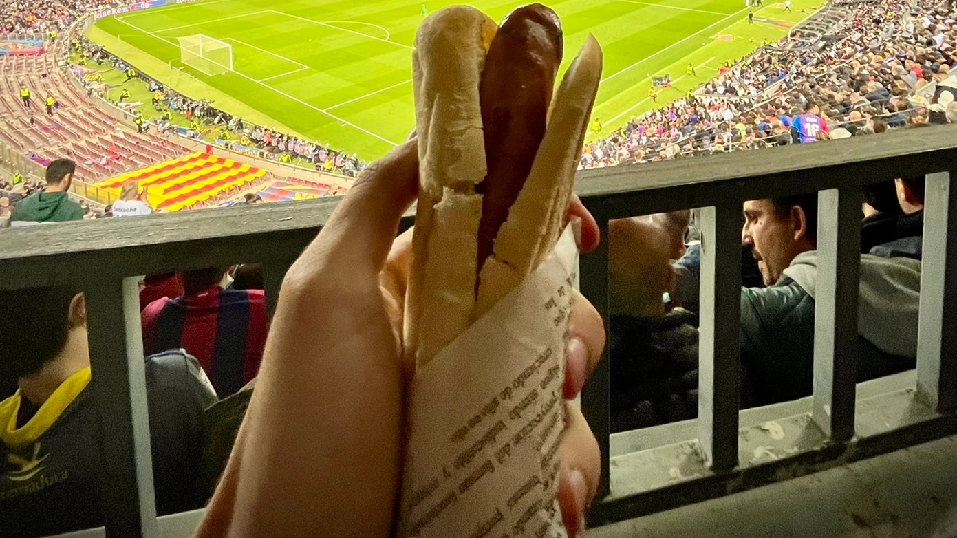 Un aficionado comiendo una salchicha en el Camp Nou