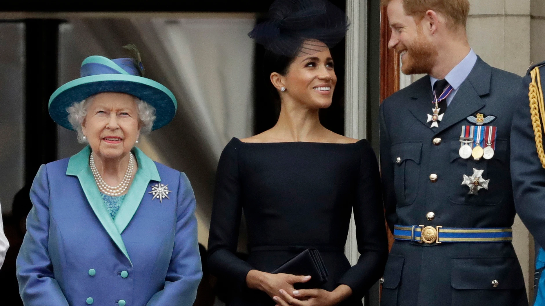 Meghan Markle y el príncipe Harry, sonrientes tras la reina Isabel II en una imagen de 2018