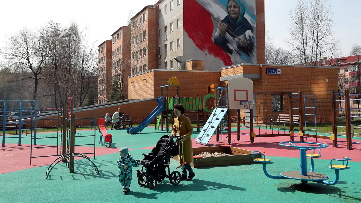 Una mujer con un cochecito camina en un patio de recreo en Reutov, en las afueras de Moscú, Rusia. Cerca de Moscú