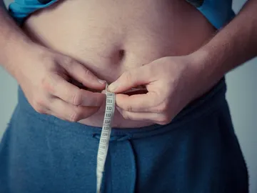 Un hombre mide la circunferencia de su barriga Un hombre mide la circunferencia de su barriga