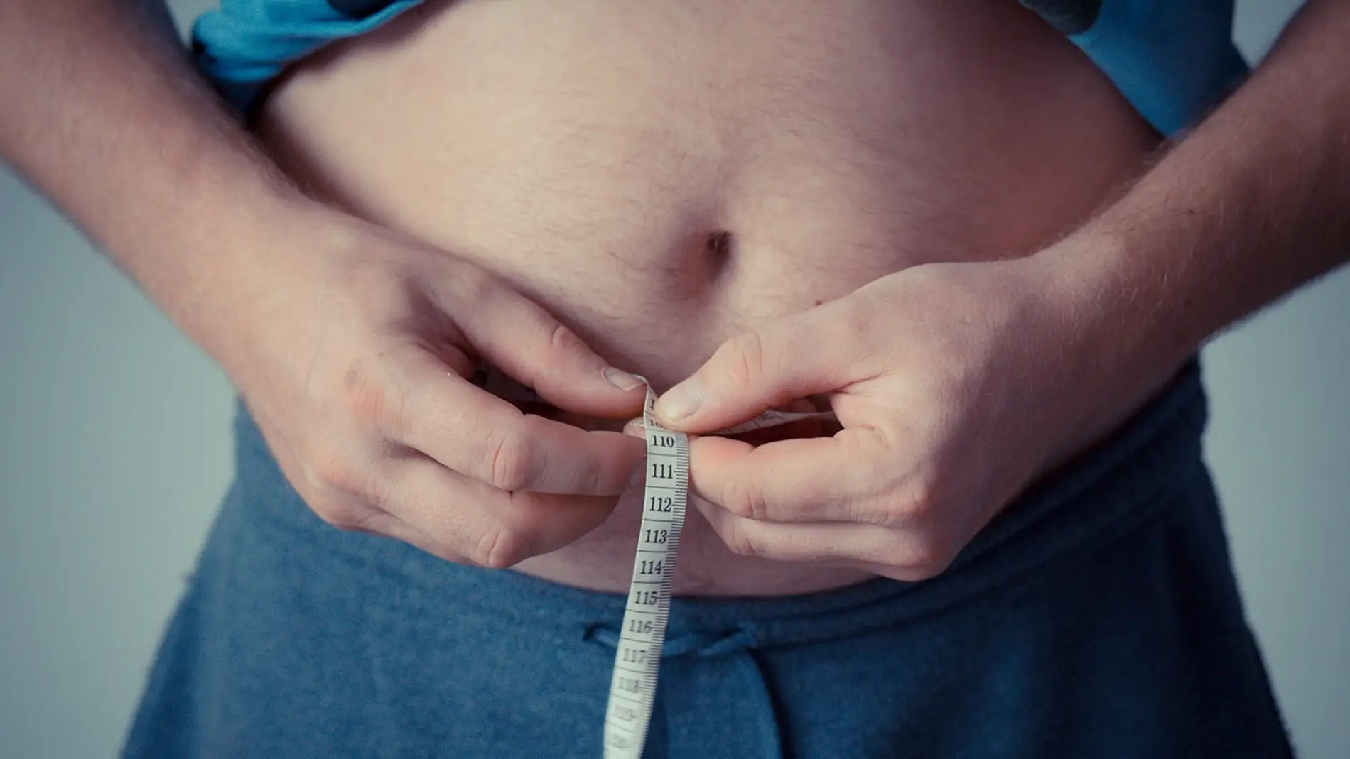 Un hombre mide la circunferencia de su barriga Un hombre mide la circunferencia de su barriga