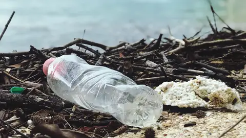 Botella de plástico abandonada en la playa Botella de plástico abandonada en la playa
