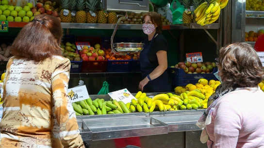 Una trabajadora de una frutería del Mercado Central de Valencia atiende a dos clientas  Una trabajadora de una frutería del Mercado Central de Valencia atiende a dos clientas
