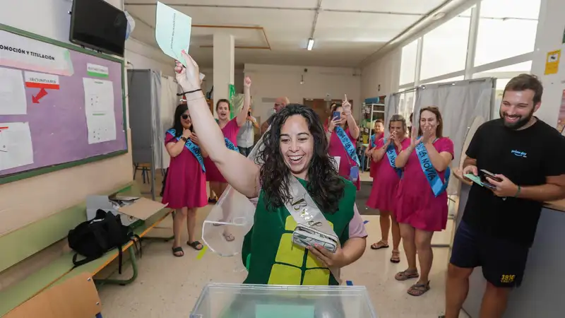 Una joven con velo y disfrazada para celebrar su despedida de soltera se dispone a introducir su papeleta de voto en una urna.