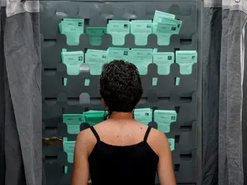 Una mujer observa las papeletas para ejercer su derecho al voto durante el día de las elecciones a la presidencia de la Junta de Andalucía a 19 de junio