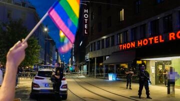 Una persona sostiene una bandera LGTBI cerca de la escena del tiroteo en Oslo, Noruega
