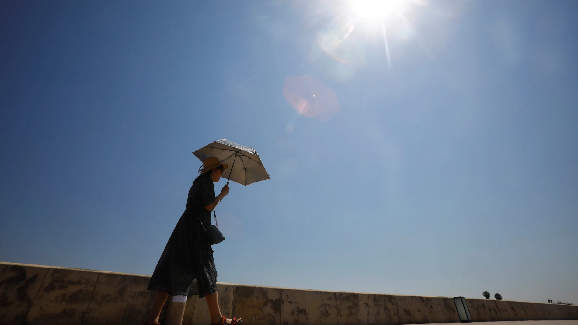 Imagen de archivo de una mujer que se protege del sol con un paraguas
