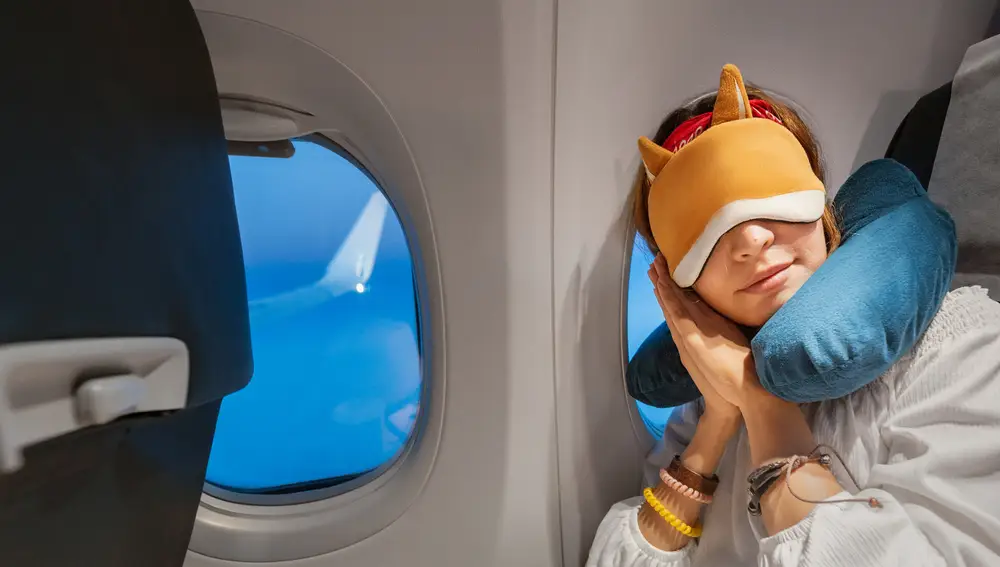 Chica durmiendo en el avión con cojín