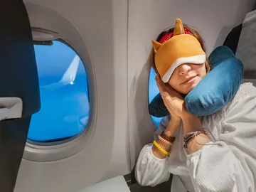Chica durmiendo en el avión con cojín Chica durmiendo en el avión con cojín