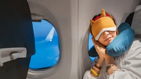 Chica durmiendo en el avión con cojín Chica durmiendo en el avión con cojín