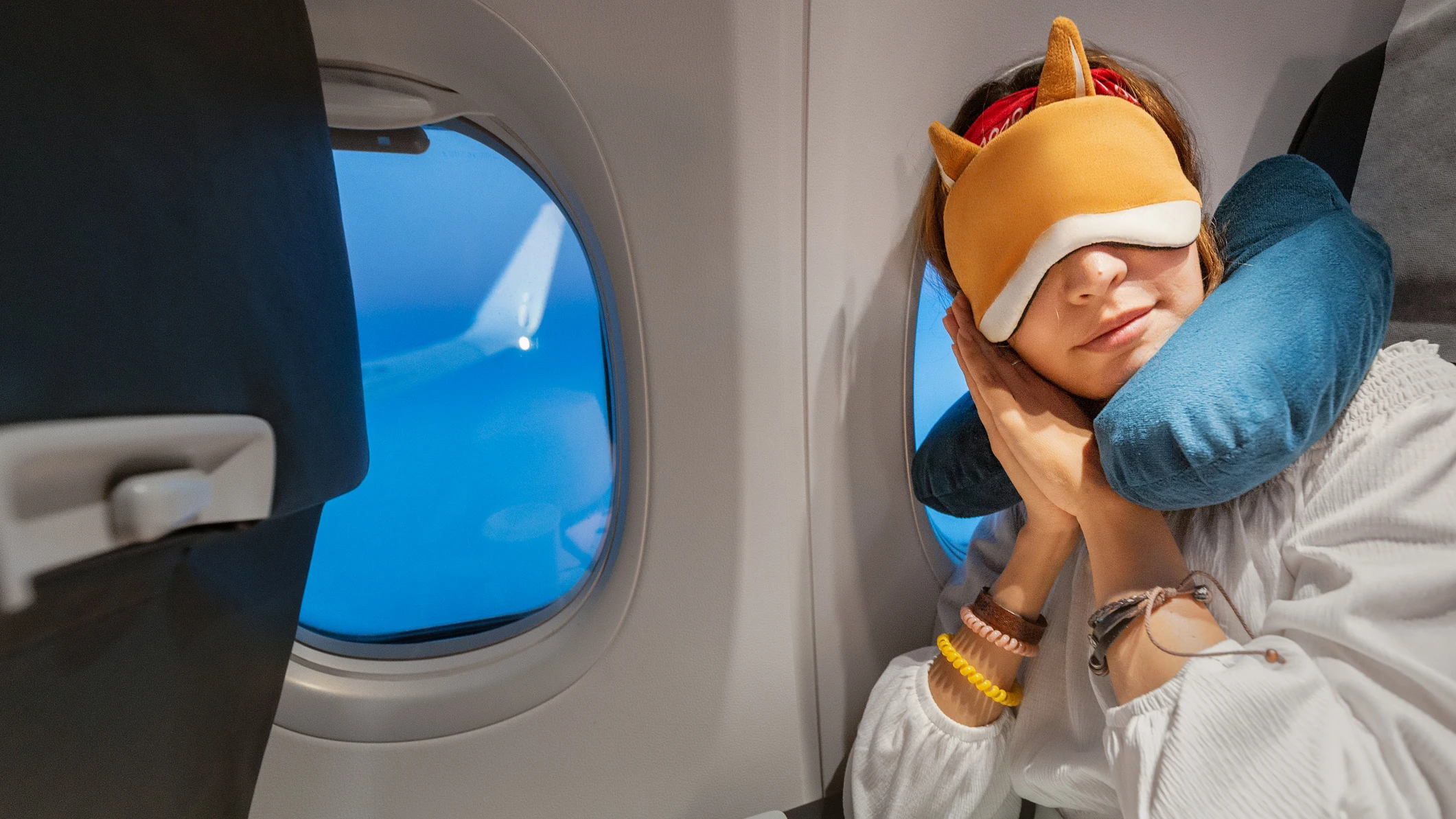 Chica durmiendo en el avión con cojín Chica durmiendo en el avión con cojín
