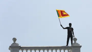 Un manifestante agita la bandera nacional mientras los manifestantes irrumpen en la oficina del primer ministro en Colombo, Sri Lanka