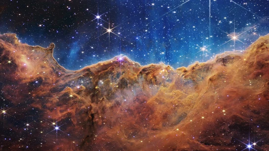 Imagen del borde de una región cercana y joven donde se forman estrellas, llamada NGC 3324, en la Nebulosa de Carina, que se asemeja a un paisaje de "montañas" y "valles" salpicados de estrellas brillantes. Imagen del borde de una región cercana y joven donde se forman estrellas, llamada NGC 3324, en la Nebulosa de Carina, que se asemeja a un paisaje de "montañas" y "valles" salpicados de estrellas brillantes.