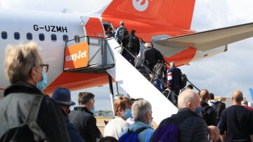 Imagen de un grupo de pasajeros británicos esperando a entrar al avión.