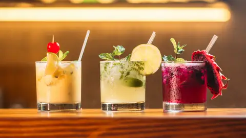 Cócteles en vaso corto decorados con frutas, hierbas aromáticas y cañitas Cócteles en vaso corto decorados con frutas, hierbas aromáticas y cañitas