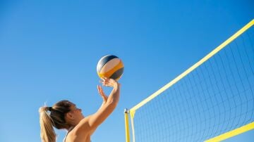 Una chica juega a voleibol en la playa.
