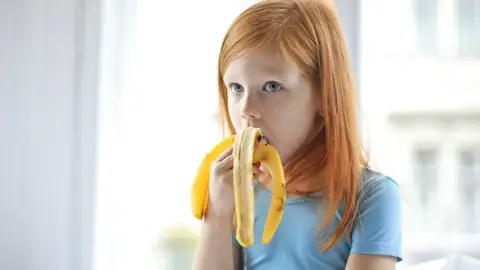 Niña comiendo un plátano Niña comiendo un plátano