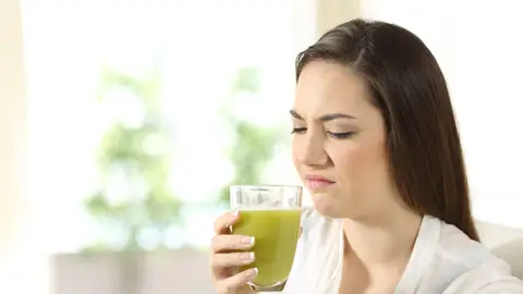 Cara de asco Mujer con cara de asco ante una bebida verde