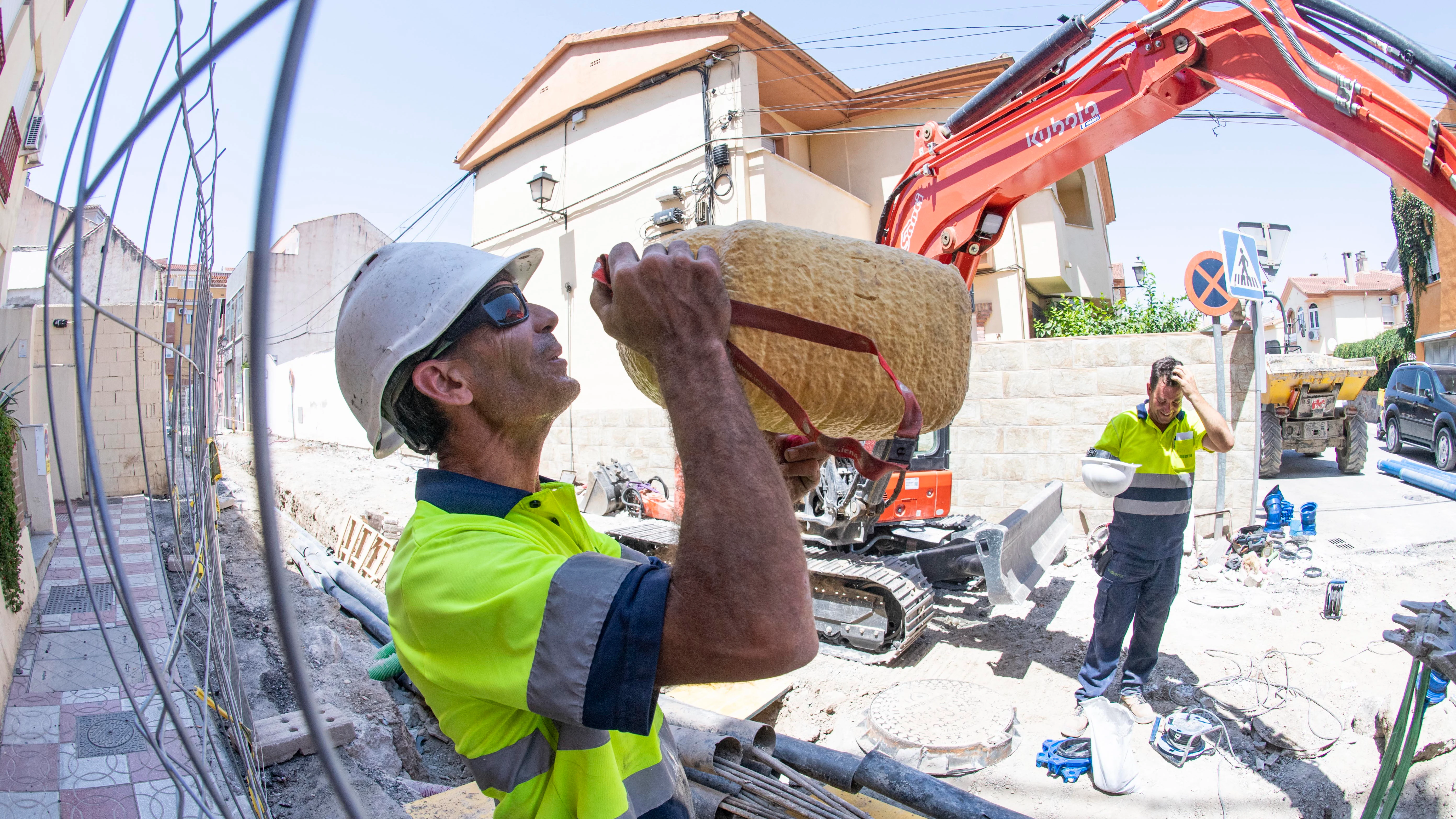 Un operario bebe agua en un descanso mientras realiza tareas de canalización de aguas en una calle de Granada